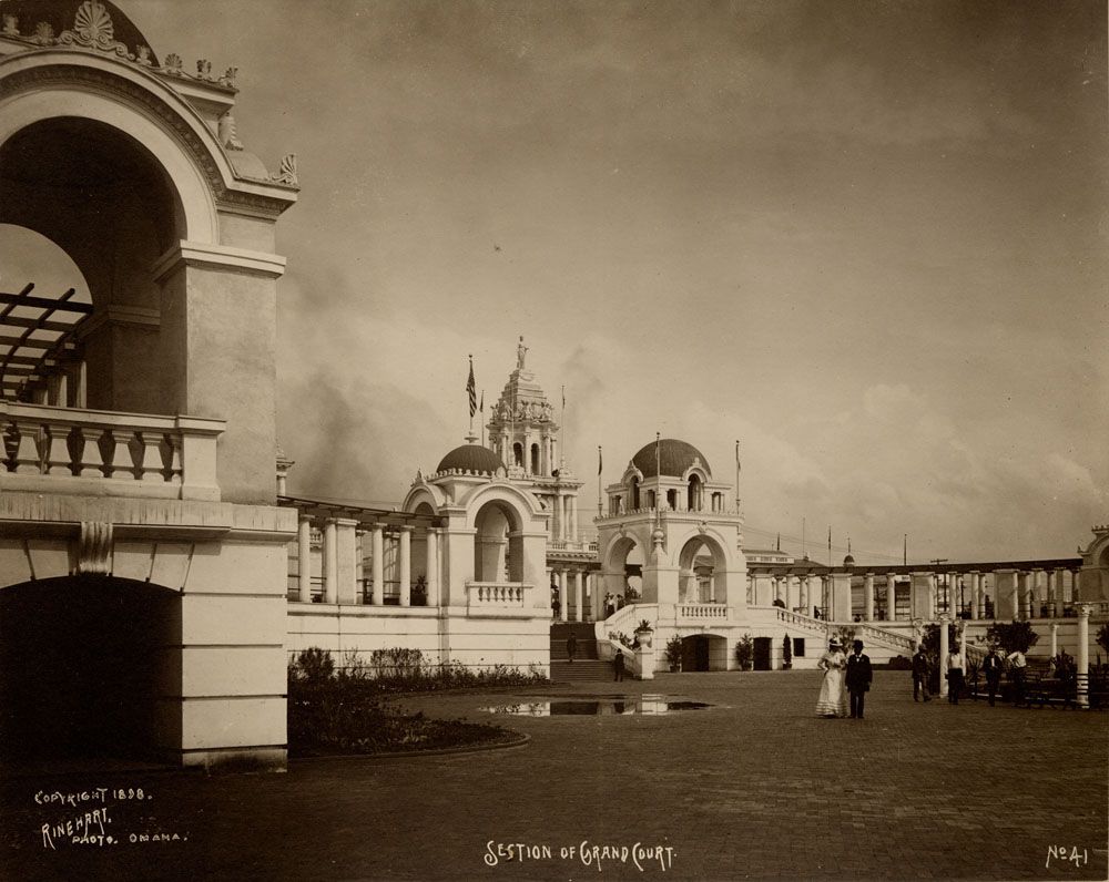 One of Twin Towers Restaurants visible behind Grand Colonnade, looking southeast. A few people walking.