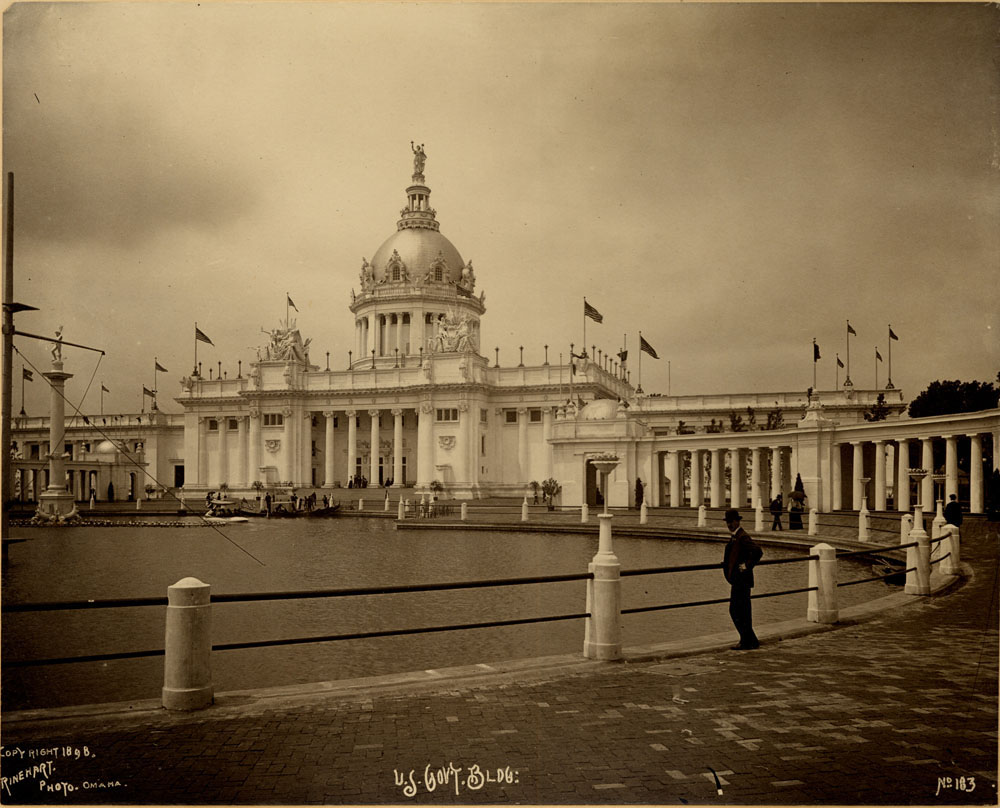 U.S. Government Building looking southwest. Swan boat, gondola, and Fountain of Neptune visible. Fountain turned off. Man standing next to lagoon and a few people walking.