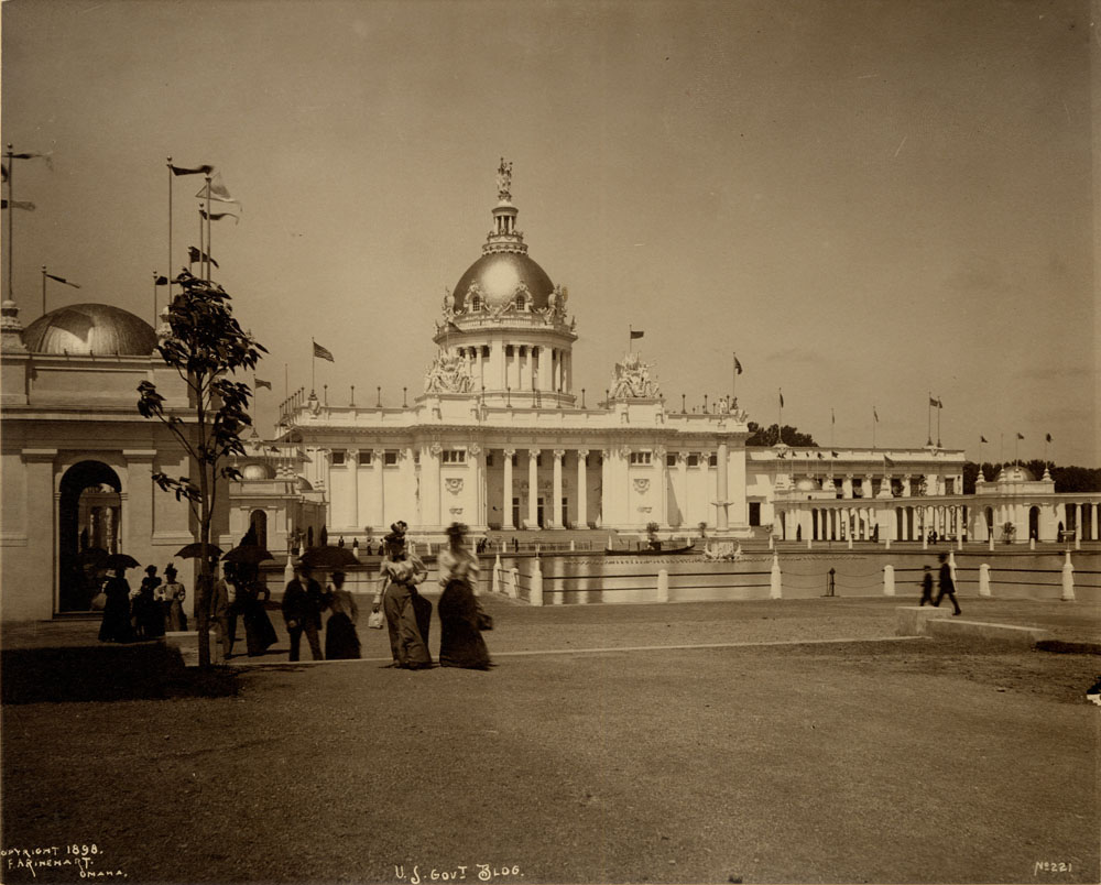 View of U.S. Government Building and colonnade northwest across lagoon. People walking in foreground.