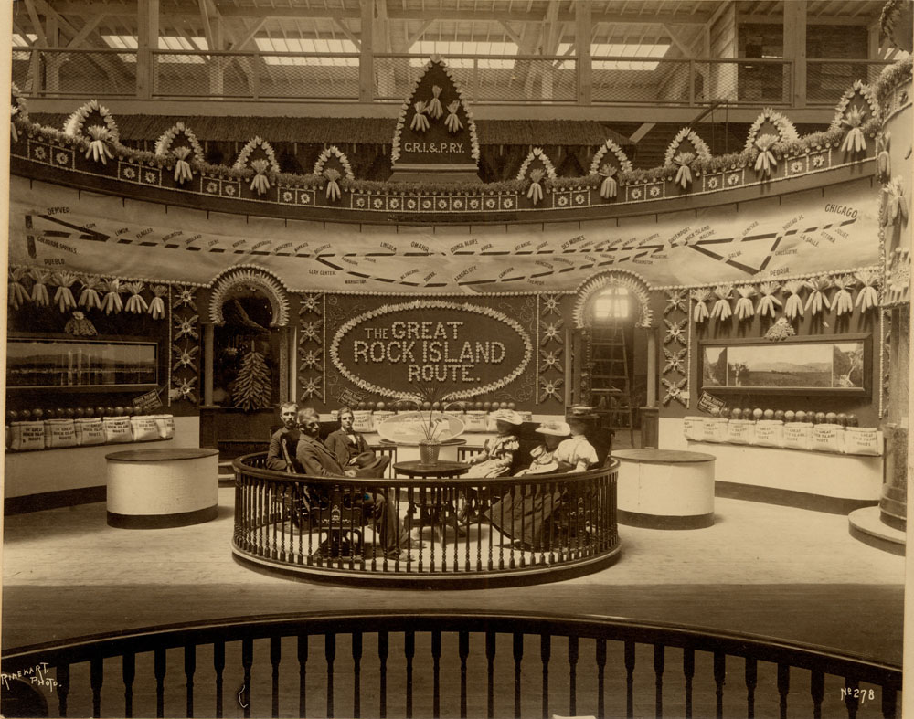 Interior of Agriculture Building. The Great Rock Island Route C.R.I & P.R.Y Railroad Exibit. Three men and three women seated.