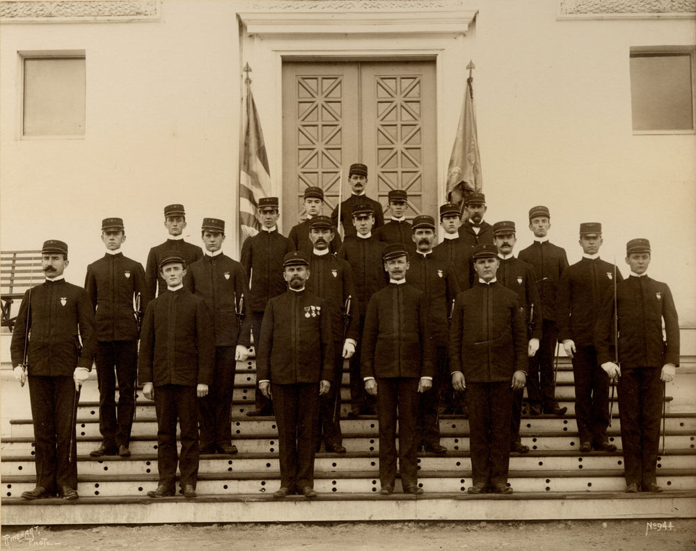 Group portrait of Omaha Guards, Company G, posing on entrance steps to an unidientified building.