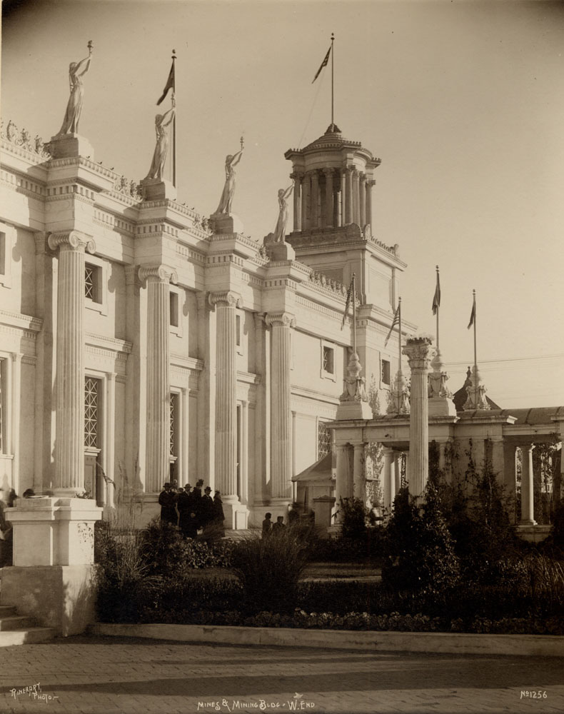 Detail of west end of Mines and Mining Building, leading to colonnade. Small group of people stand in front.