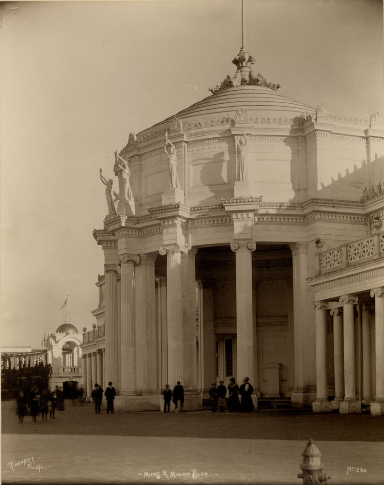 Close up of Mines and Mining Building, looking northeast. Grand Colonnade to the east. A few people stand, walk, or are seated.