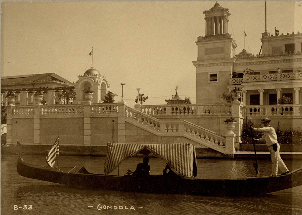Gondola with passengers in lagoon. At base of balustraded staircase in front of Mines and Mining Building. Corner of Mines and Mining Building and southeast portion of Grand Colonnade visible.