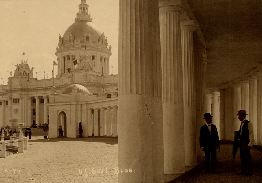 U.S. Government Building looking southeast from west colonnade. Two men stand within colonnade, and others walk near building.