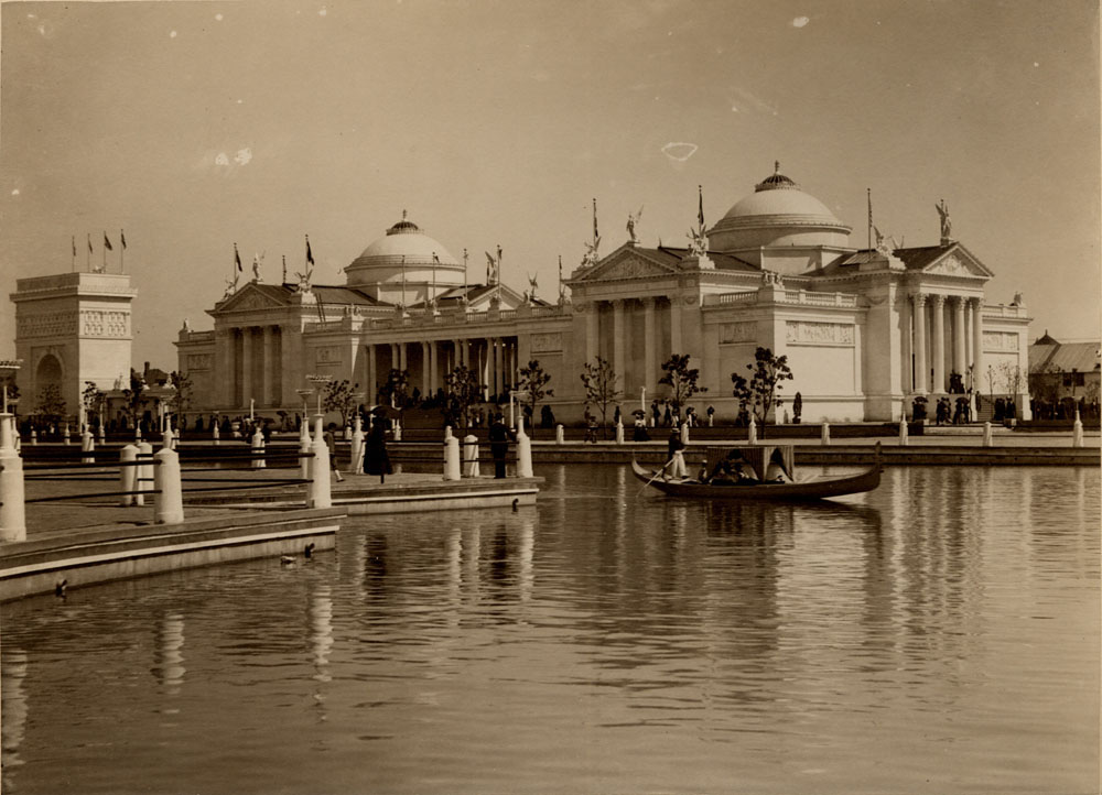 Fine Arts Building looking southeast, across lagoon. Arch of States to east. People walking. Gondola in lagoon.