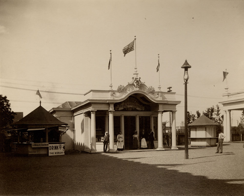 Rinehart Studio, Official Photographer. Two men and three women pose in front of building. A man stands to the side. Corner of Boys and Girls Building to the east. Concession Stand to the west, selling: "The World's Fair Drink, Orange Cider 5 cents."