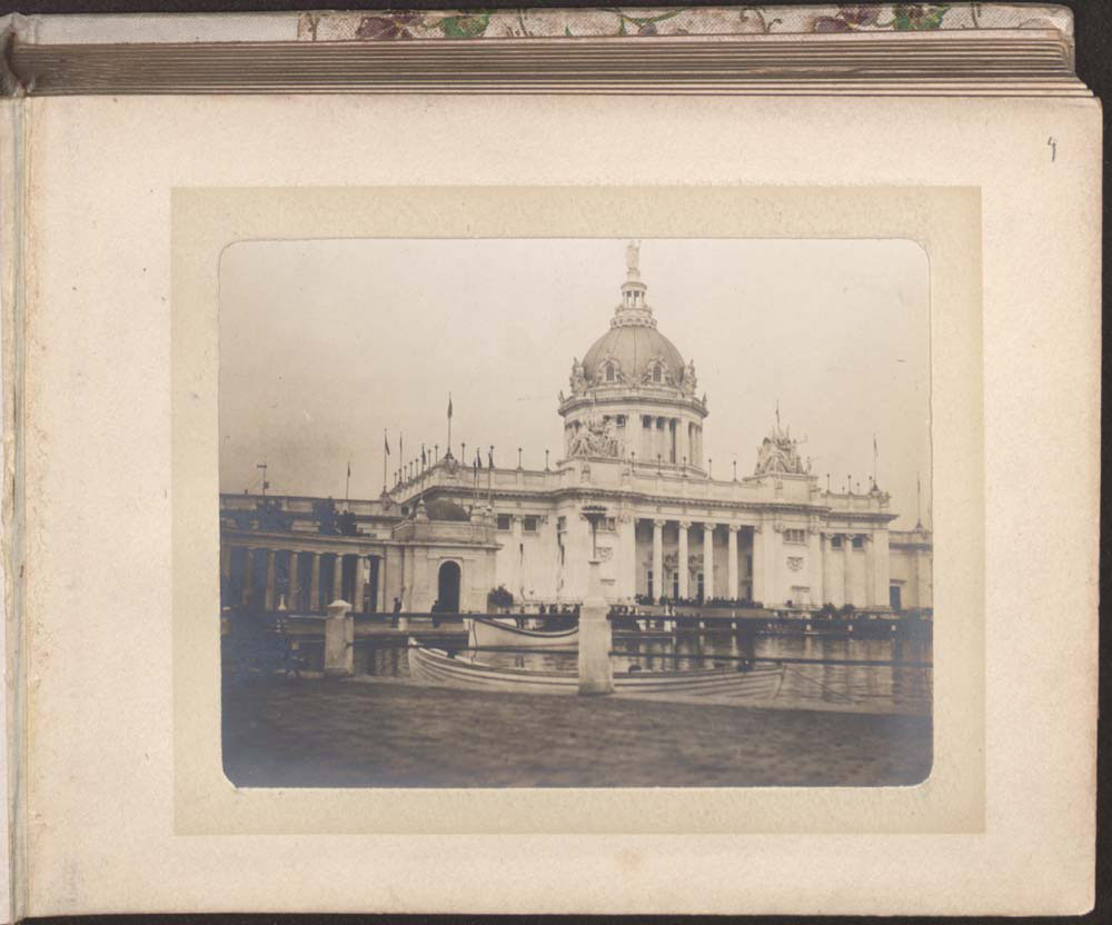 U.S. Government Building and portion of south west colonnade. Crowd seated on steps. Lagoon with docked boats.