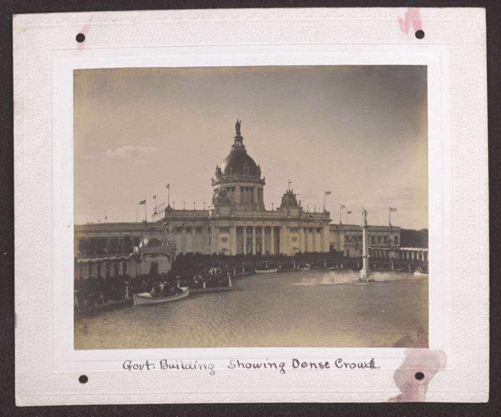 U.S. Government Building with heavy crowd gathered. U.S. Lifesaving Service boat docked. Swan Boat and Gondolas in water. Fountain of Neptune waters turned on at low height.