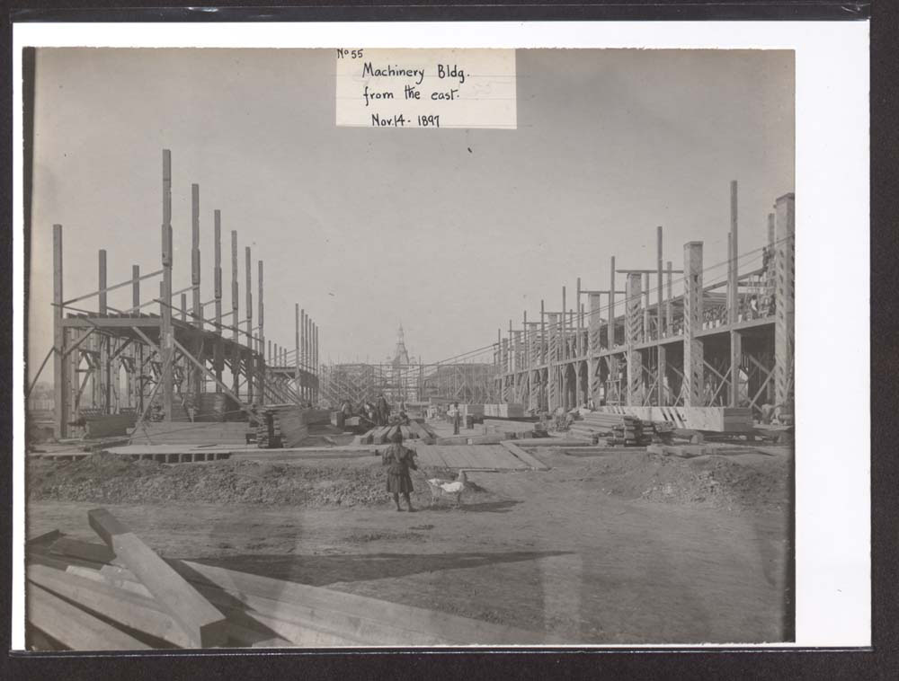 Woman with baby carriage views construction of Mines and Mining Building. Administration Arch visible to the west.