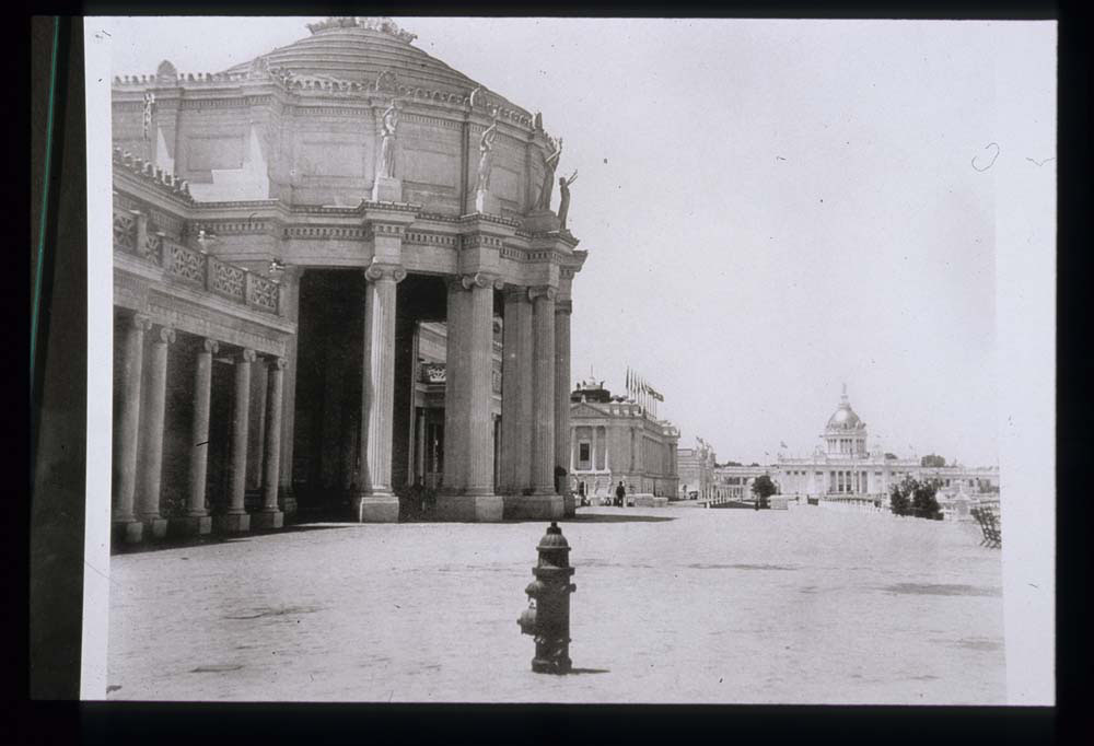 Mines and Mining Building, looking west. Liberal Arts, Fine Arts, and U.S. Government Buildings in background. Fire hydrant in foreground.