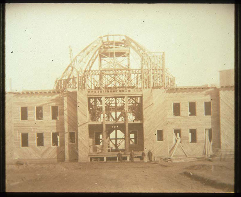 Construction of Nebraska Building. Four men pose in front of building.